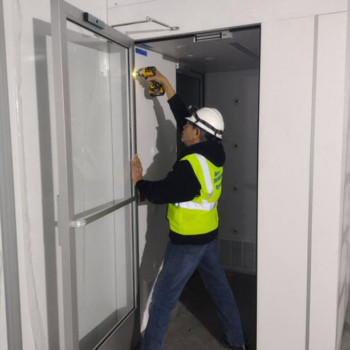 assembling cleanroom air shower, construction worker with yellow vest, air shower door