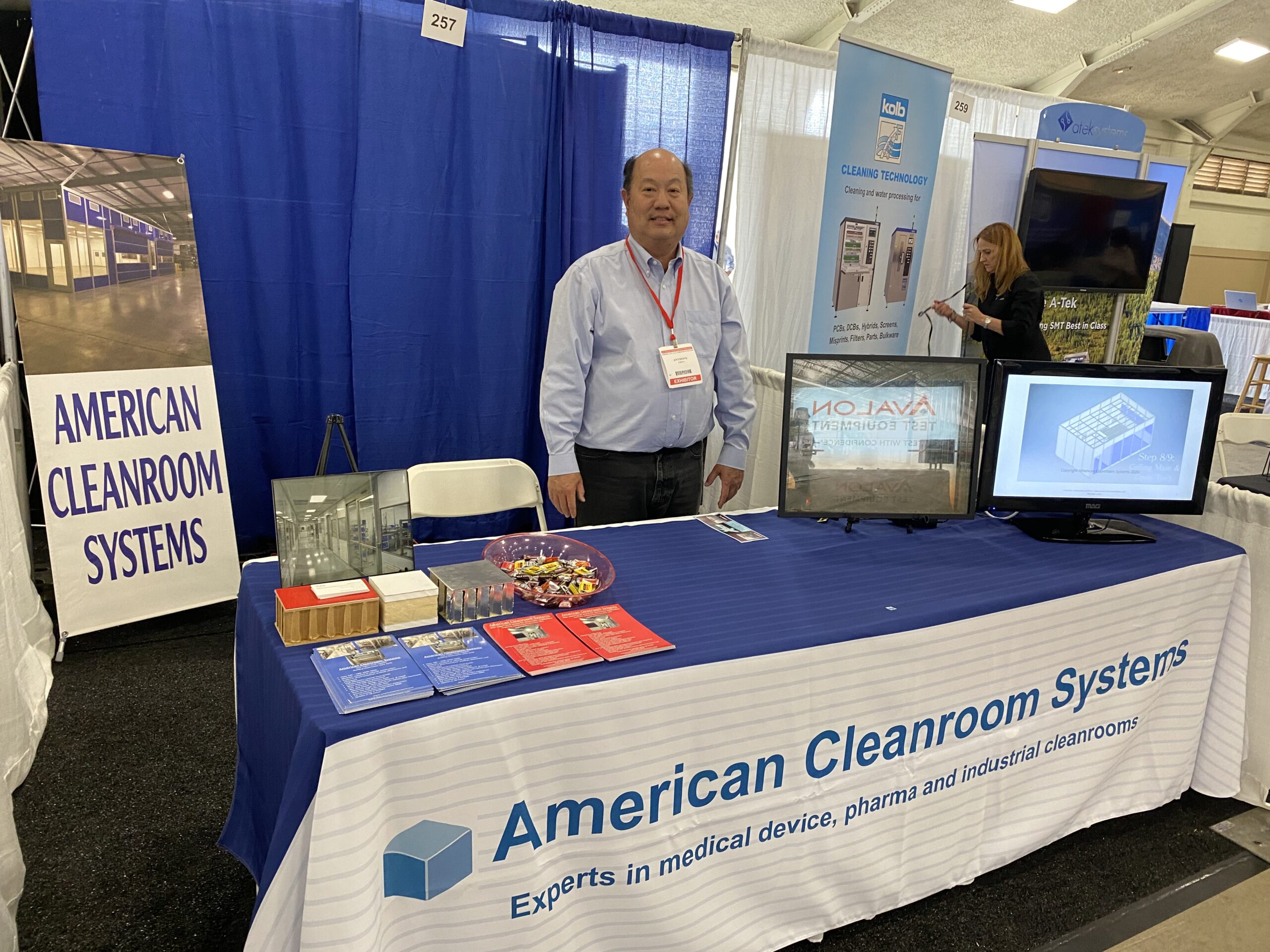 american cleanroom systems tradeshow booth with monitors and booklets on table